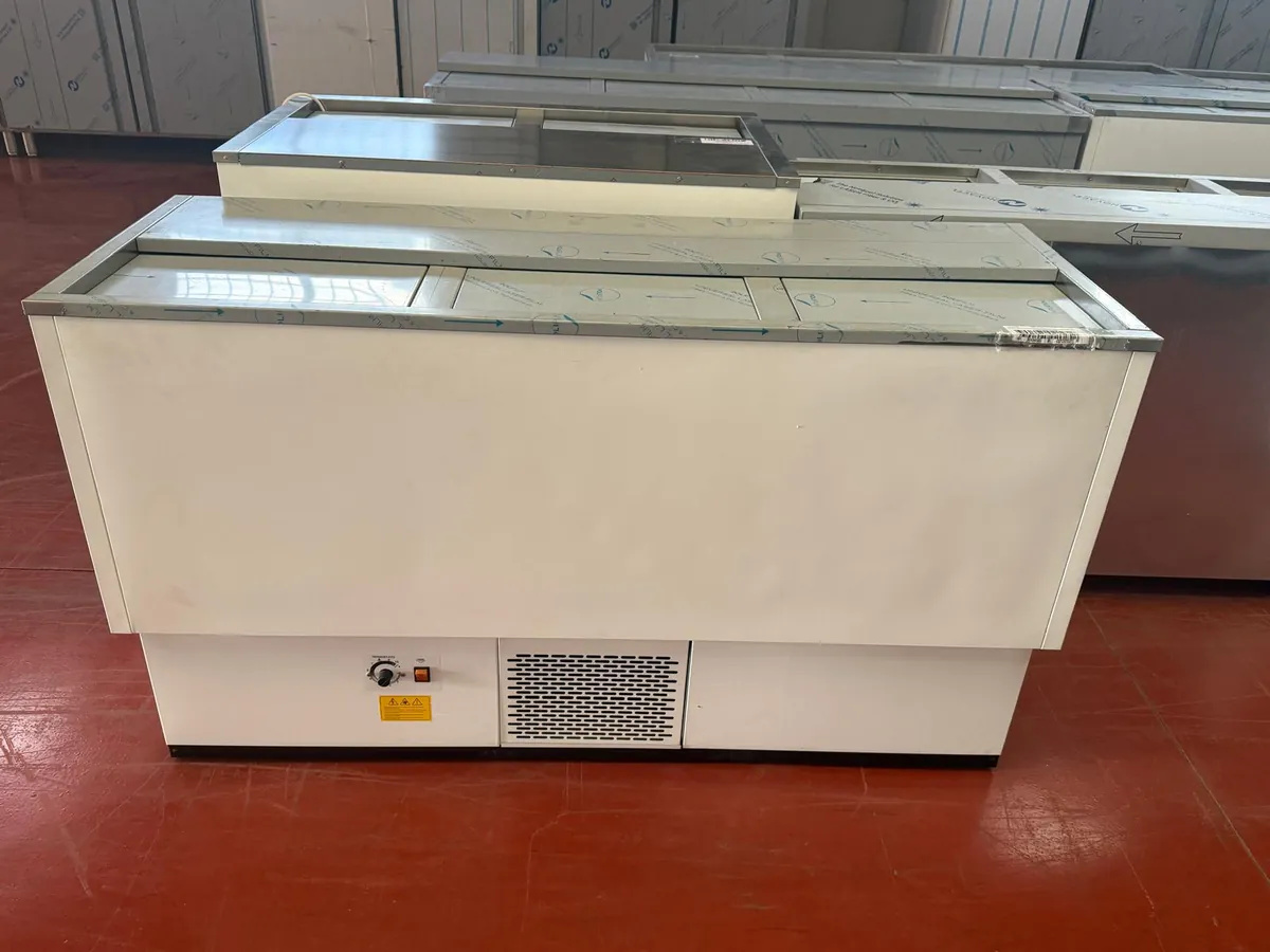 Botellero refrigerado de frente blanco y tres tapas, con termostato mecánico y rejilla de ventilación, junto a otros equipos en la nave de Frinus